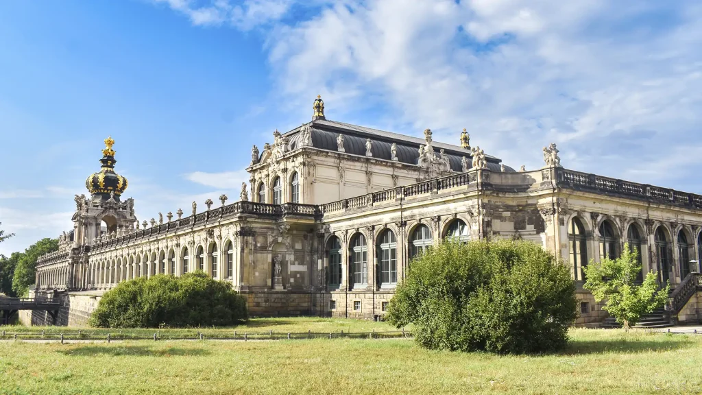 Außenansicht des Dresdner Zwingers mit dem markanten Kronentor unter blauem Himmel in Sachsen.