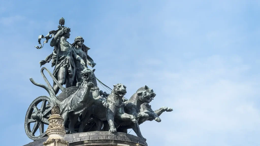 Bronzestatue der Panther-Quadriga mit Dionysos und Ariadne auf dem Dach der Semperoper in Dresden vor blauem Himmel.